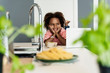 © Westend61 - Happy girl with laptop in kitchen