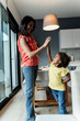 © Westend61 - Happy mother and daughter high fiving in kitchen