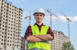 © vadimalekcandr - civil engineer in white helmets and a yellow vest on the background of the house under construction.