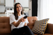 © Westend61 - Happy young woman sitting on couch at home watching Tv