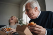 © Westend61 - Happy grandfather and grandson eating burger together at home