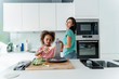 © Westend61 - Girl cooking with mother in kitchen grating cheese