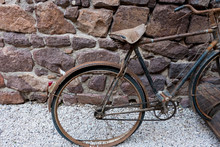 Old Rusty Bicycle In Front Of A Rock Wall