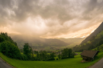 Wall Mural - Rain and hail storm over a mountain landscape is illuminated by the setting sun