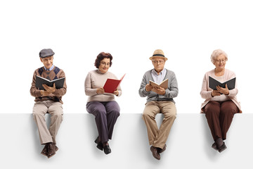 Wall Mural - Group of elderly people sitting on a white panel reading books