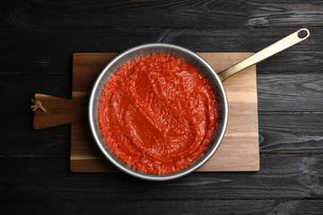 Delicious tomato sauce in pan on black wooden table, top view