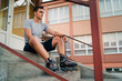 © Miljan Živković - Portrait of young man in roller blade skates sitting on the stairs of the high school wearing gray t shirt and shorts in summer day