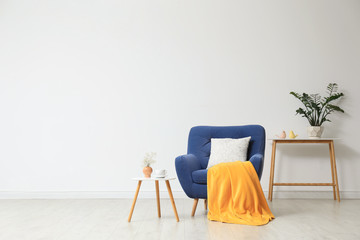 Poster - stylish living room interior with comfortable blue armchair near white wall. space for text