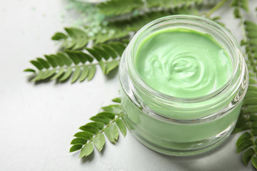 Professional face mask with leaves on light table, closeup. Space for text