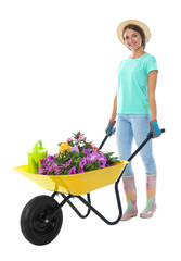 Female gardener with wheelbarrow and plants on white background