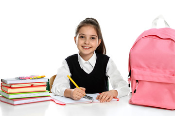 Poster - Little girl in uniform doing assignment at desk against white background. School stationery