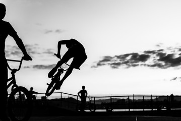 Wall Mural - BMX cyclists training in a late afternoon in black and white