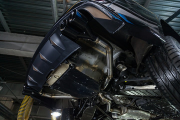 Wall Mural - Bottom view of the car on a bifurcated exhaust system, rear bumper with a sports diffuser and nozzles in black. Tuning and atom service industry.