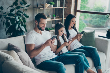 Sticker - Profile side view of nice attractive cheerful focused family wearing casual white t-shirts jeans denim sitting on sofa using modern technology at industrial loft style interior living-room