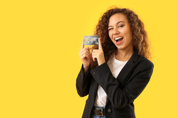 Wall Mural - Beautiful African-American woman with credit card on color background