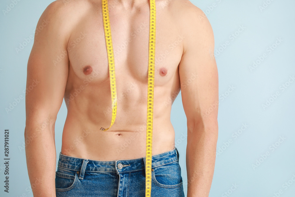 Handsome muscular man with measuring tape on color background. Weight loss concept