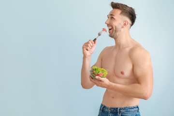 Sticker - Handsome muscular man with salad on color background. Weight loss concept