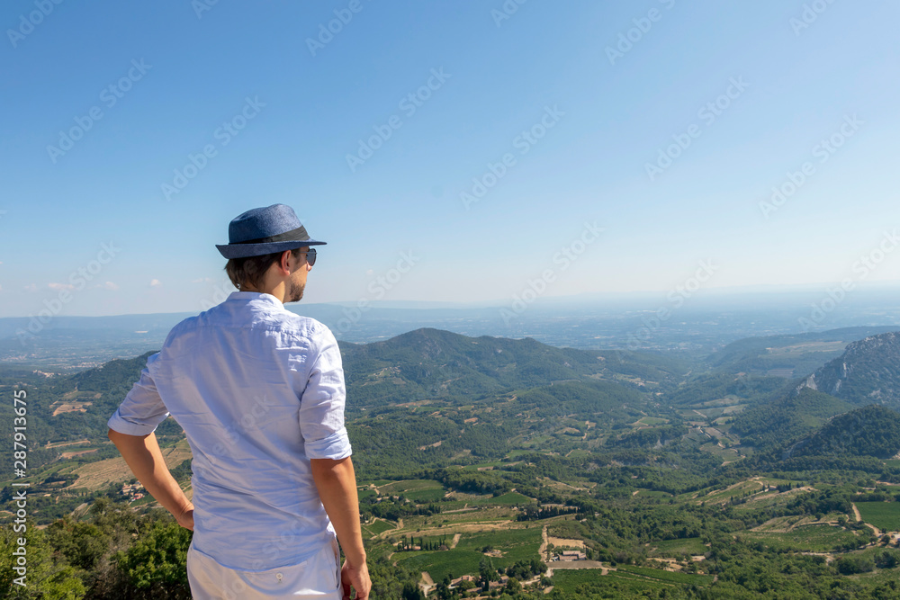 Young handsome man travel back view in mountains, caucasian male traveler in Provence in Vaucluse, France - obrazy, fototapety, plakaty 
