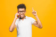 © denis_vermenko - Portrait of a happy african american guy talking on mobile phone isolated against yellow background.