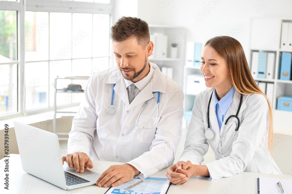 Male and female doctors working at table in clinic