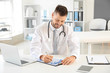 © Pixel-Shot - Male doctor working at table in clinic