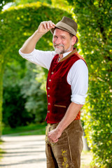 handsome bavarian man in his 50s standing outdoors in park