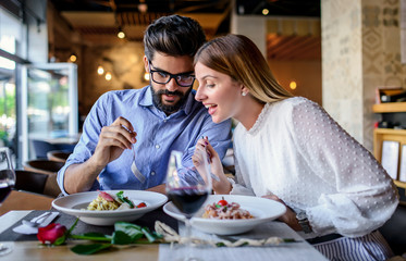 Paste and red wine. Young couple enjoying lunch in the restaurant. Lifestyle, love, relationships, food concept