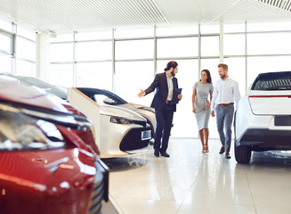 Wall Mural - Couple and the dealer selling cars look the car in the showroom.