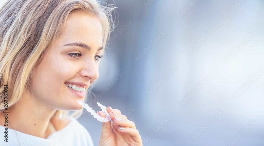 Invisalign orthodontics concept - Young attractive woman holding - using invisible braces or trainer - obrazy, fototapety, plakaty 