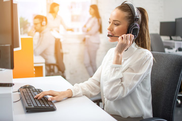 Beautiful young happy smiling female customer support phone operator at workplace.