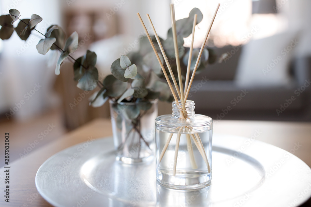 decoration, hygge and aromatherapy concept - aroma reed diffuser and branches of eucalyptus populus on table at home - obrazy, fototapety, plakaty 
