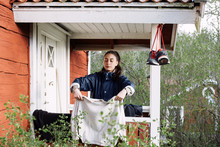 Young Woman Drying Clothes While Standing Outside Cottage