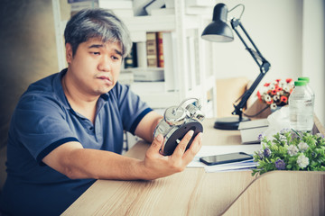 Wall Mural - Blurred of Asian midle-ages man, He is patient from neurological diseases, or hemiplegia having a facial palsy, He is looking at the alarm clock in his hand, to health and paralysis concept.