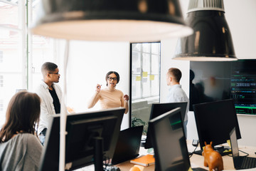 Computer programmers discussing while standing in creative office