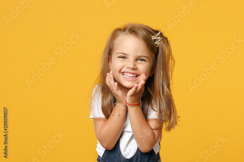 Fotomural Little cute child kid baby girl 4-5 years old wearing light denim clothes isolated on pastel yellow wall background, children studio portrait