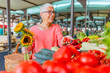 © Dragana Gordic - Senior woman shopping on the market healthy vegetables and fruits. Woman buying red peppers at the market. Woman buys fruits and vegetables at a market. Fresh and healthy food.