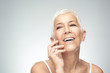 © chika_milan - Beautiful smiling senior woman with short gray hair posing in front of gray background. Beauty photography.