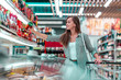 Young woman with shopping cart chooses and buying products at the grocery store. Buying food at supermarket