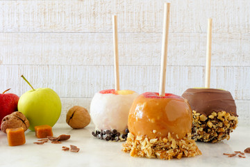 Wall Mural - Three types of autumn candy apples with caramel and chocolate against a bright wood background