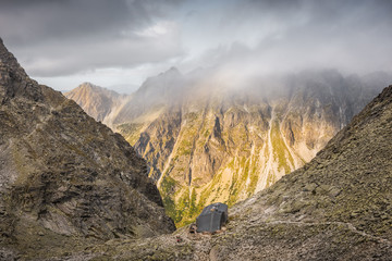 Wall Mural - Mountain Landscape with Cottage under Rysy Peak as Seen from Sedlo Vaha at Sunrise with Golden Light in High Tatras, Slovakia