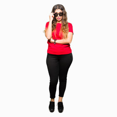 Sticker - Young beautiful woman wearing red t-shirt and sunglasses skeptic and nervous, disapproving expression on face with crossed arms. Negative person.