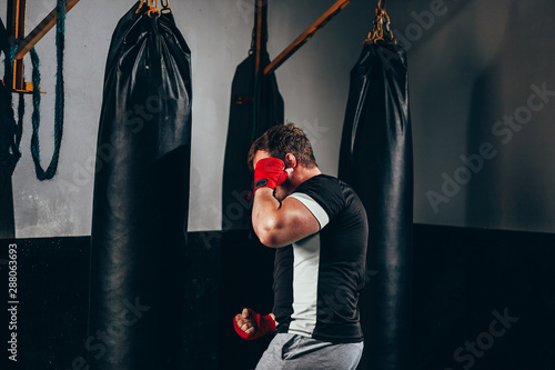 фотографія Muscular kickbox fighter exercising with punch bag at the gym
