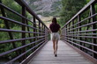 © Kaichi - 自然の中の橋を渡る女性の背中