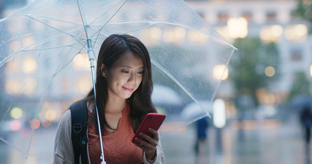 Sticker - Woman hold with umbrella and use of mobile phone in the city at night