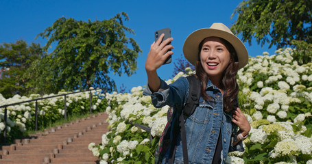 Sticker - Woman takes selfie on phone with white Hydrangea flower garden