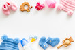 Blue and pink knitted footwear, hat, dummy, rattle and bottle frame for baby on white background top view mockup