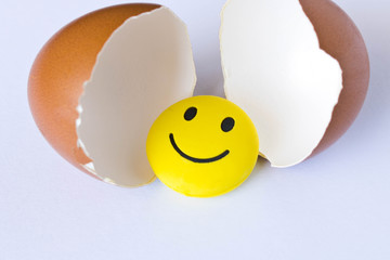 Wall Mural - Funny yellow smiley toy in an egg-shell. On white background.