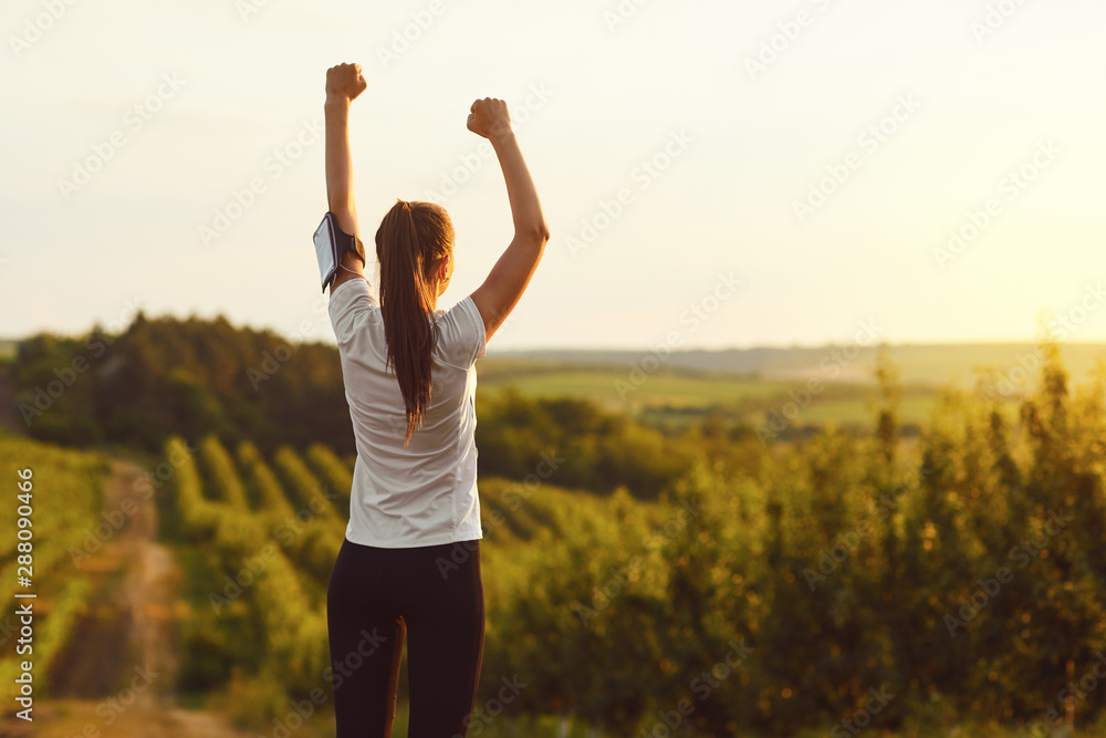 Girl raised her hands up at a training on the nature on the morning. - obrazy, fototapety, plakaty 