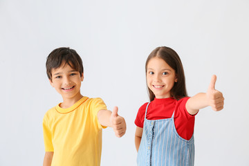 Wall Mural - Portrait of happy children showing thumb-up gesture on light background