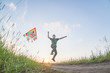 © Oleg - A child plays with a kite at sunset in the field.